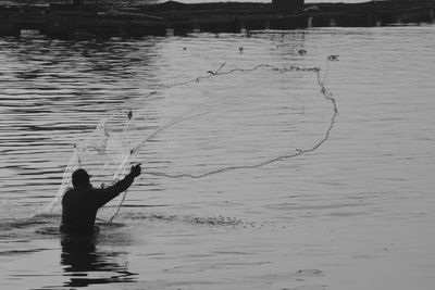 Rear view of silhouette man fishing at beach