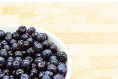 Blueberries in a rounded white bowl on a wooden table