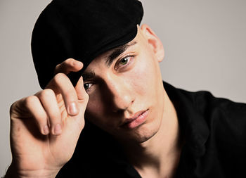 Portrait of young man wearing hat against gray background