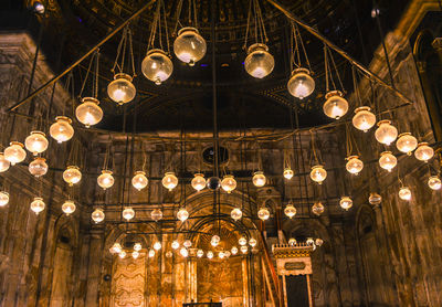 Low angle view of illuminated chandelier hanging on ceiling