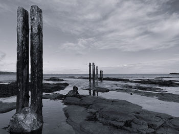 Wooden posts on beach against sky