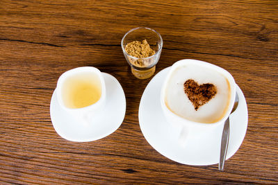 High angle view of coffee cup with herbal tea and brown sugar on table