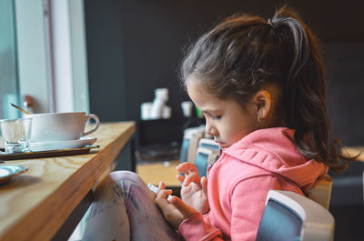 Close-up of girl using mobile phone at home