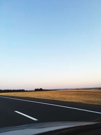 Road by landscape against clear blue sky