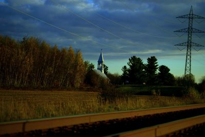 Electricity pylon against cloudy sky