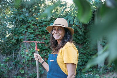 Portrait of smiling young woman standing against plants