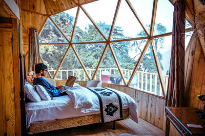 Man sitting on bed by window