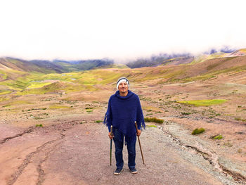 Full length portrait of hiker with hiking pole standing on land