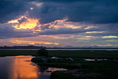 Scenic view of dramatic sky over lake during sunset