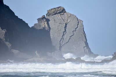 Rock formations in sea against clear sky