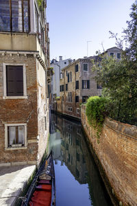 Canal amidst buildings against clear sky