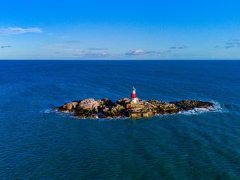 Lighthouse by sea against sky