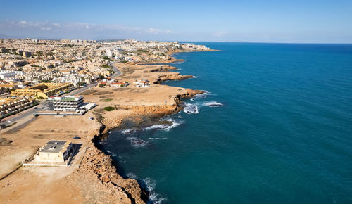 High angle view of townscape by sea against blue sky