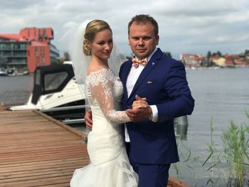 Young couple standing in front of sea against sky