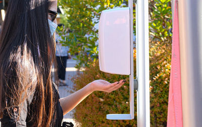 A girl with a surgical mask washes her hands with disinfectant gel at the entrance to a mall. 