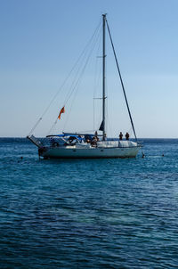 Sailboats sailing in sea against clear sky