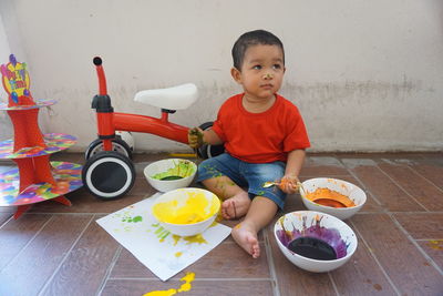 Cute boy sitting with objects at home