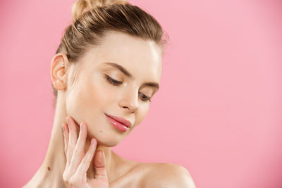 Close-up of young woman against pink background