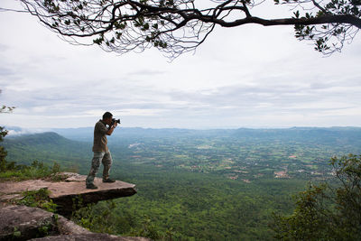 Man photographing on mountain against sky