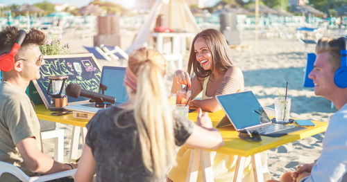 Smiling friends sitting at beach