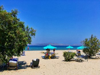 Chairs on beach against clear blue sky