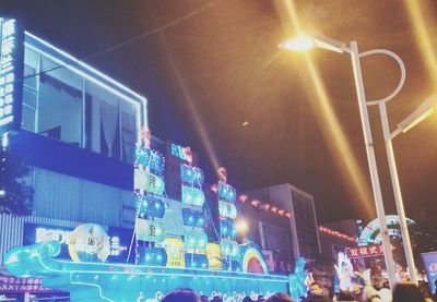 Low angle view of illuminated lighting equipment in city at night