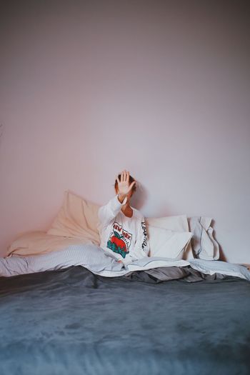 Woman showing stop gesture while sitting on bed