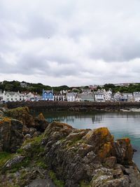 Scenic view of river by buildings in city against sky