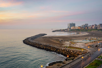 Aerial view of sea and buildings against sky during sunset