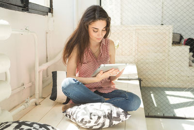 Young woman using smart phone while sitting in laptop