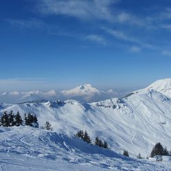 Scenic view of snow covered mountains against blue sky