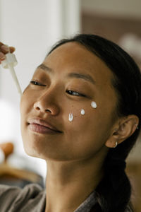 Smiling woman applying cream on face