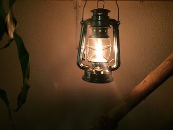 Low angle view of illuminated light bulb hanging on wall