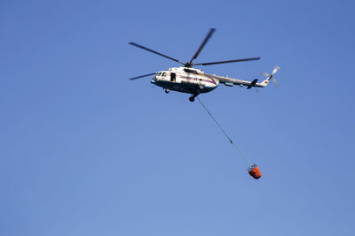 Low angle view of helicopter against clear blue sky