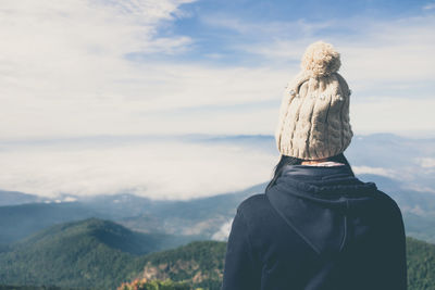 Rear view of woman standing on mountain against sky