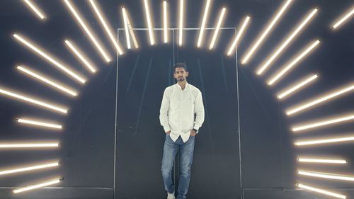 Portrait of man standing against illuminated wall