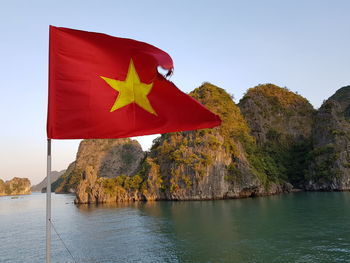 Red flag by river against sky