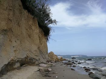 Rock formation on beach against sky