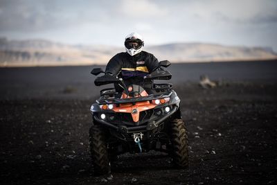 Man riding motorcycle on land against sky