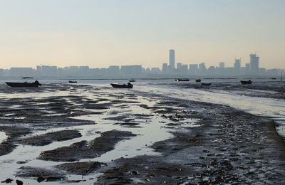 Scenic view of sea by buildings against sky during winter