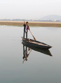 Man working on boat against sky