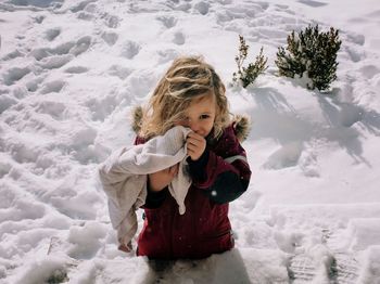 Young blonde girl standing in the snow smiling in winter