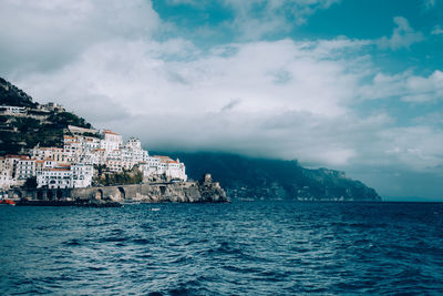 Sea by buildings against sky