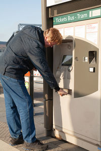 Side view of man standing by machine