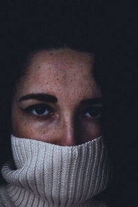 Portrait of man covering face against black background