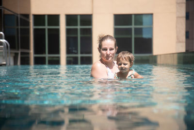 Portrait of woman swimming in pool. mother with toddler in pool