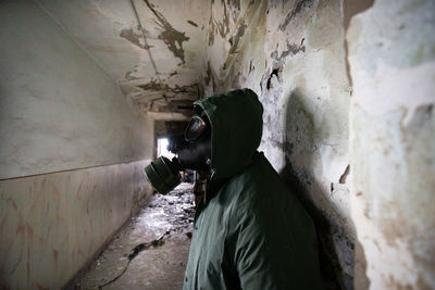 Side view of man wearing gas mask standing in abandoned building