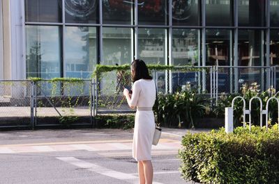 Rear view of woman standing against building