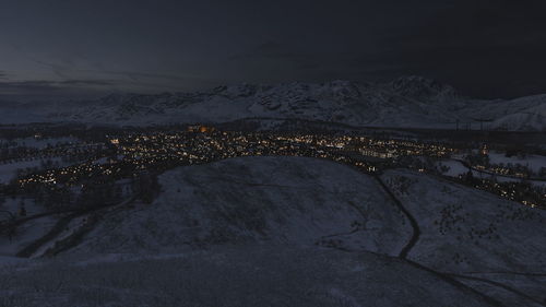 Aerial view of illuminated snowcapped mountains against sky at night