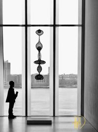 Rear view of man standing by window in building